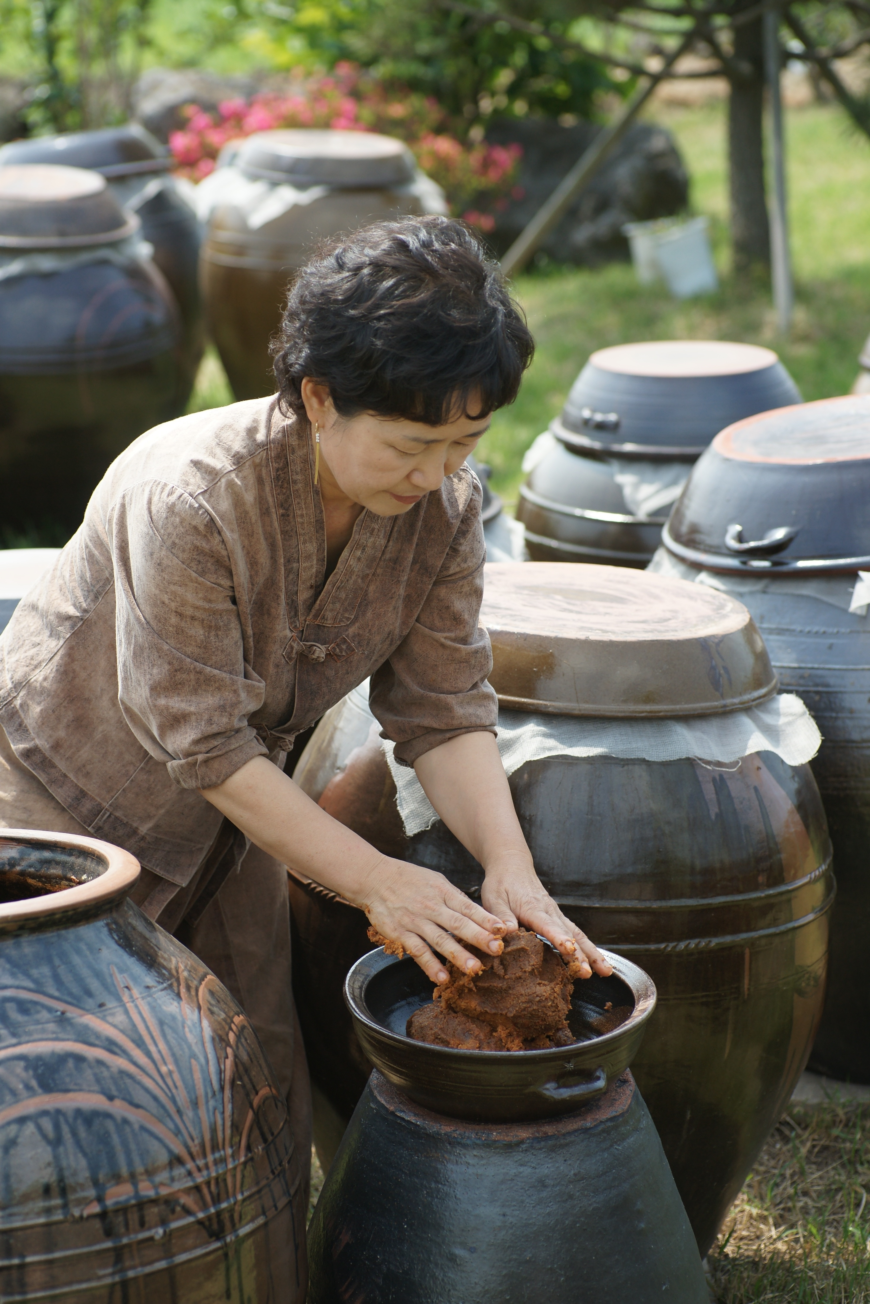 손으로 항아리에서 된장을 뜨고 있는 제주물마루된장학교 부정선 대표